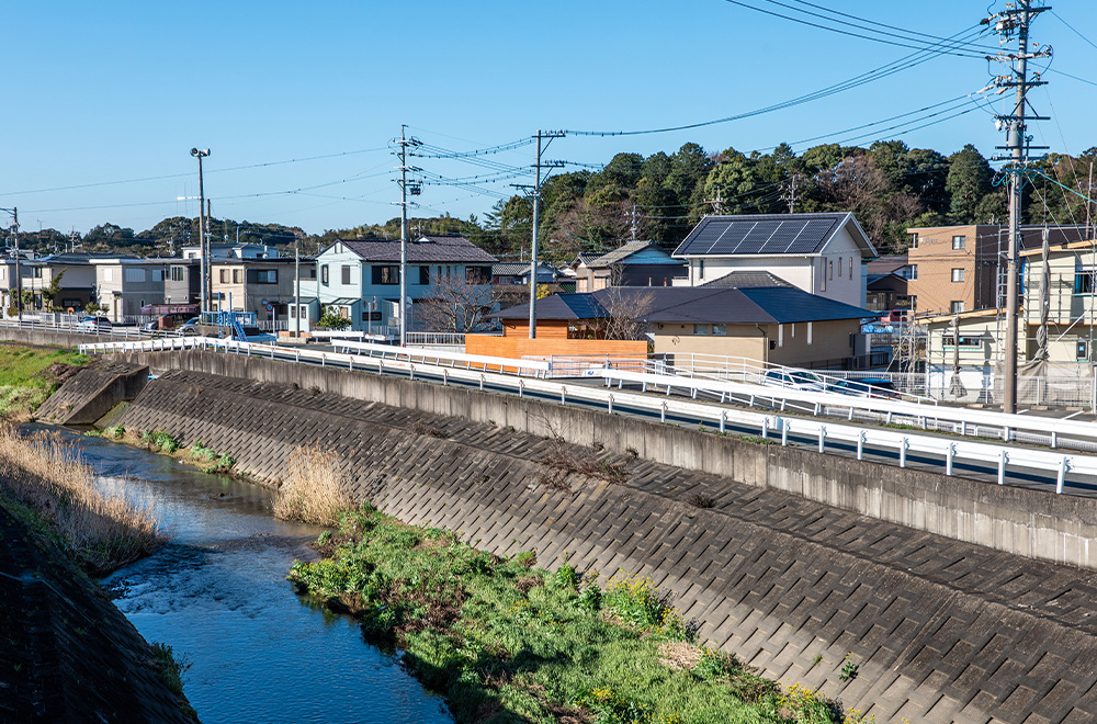 川沿いに建つ住まいの奥には小さな山々が見える