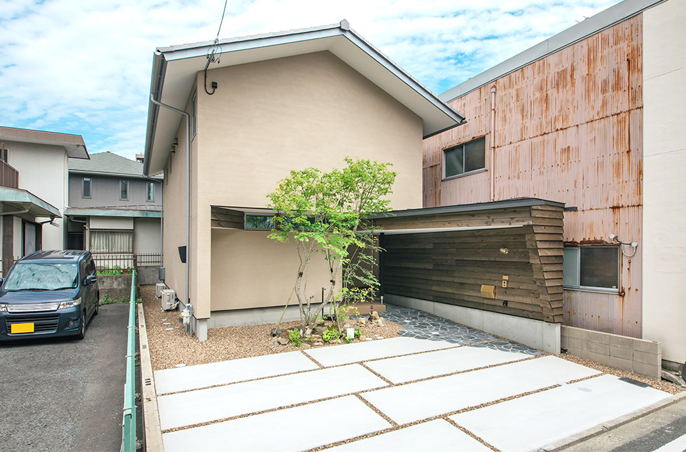 敷地環境にフィットさせた切妻屋根の2階建て住宅 玄関へのアプローチは木の壁でプライバシーを確保